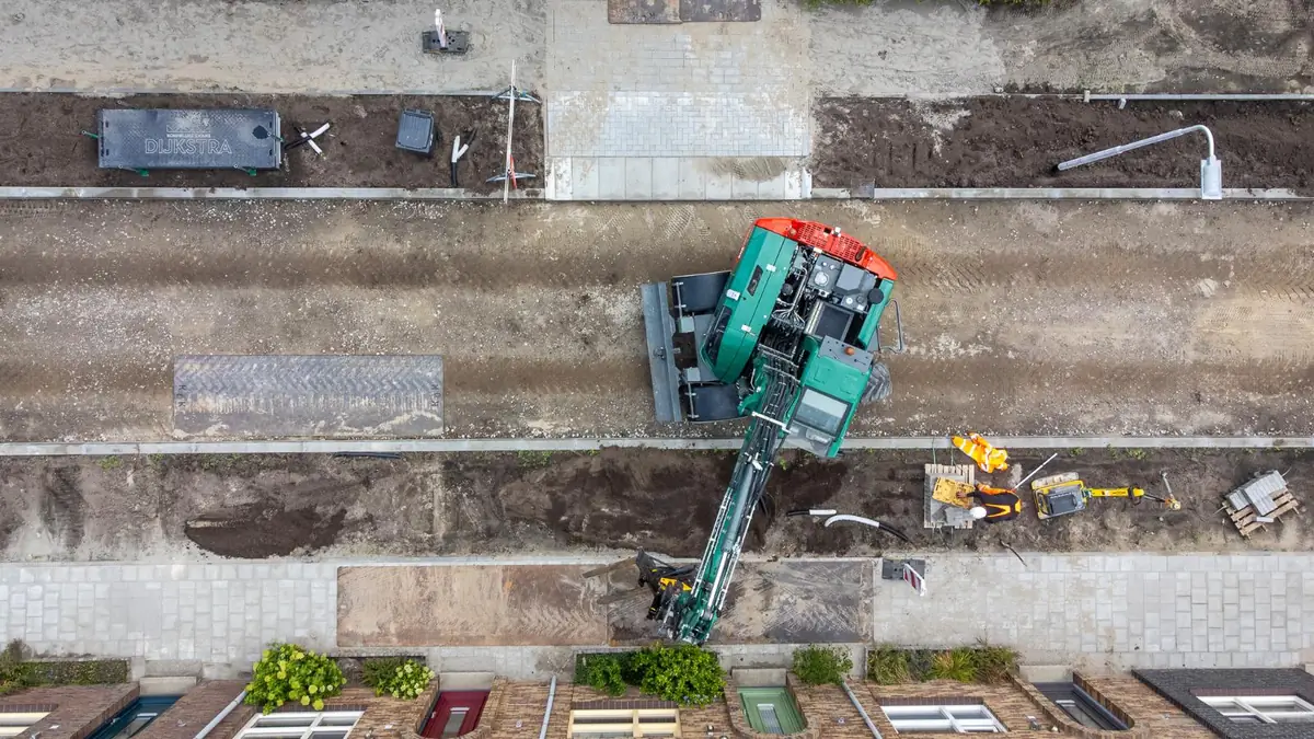Luchtfoto van grondwerk met een graafmachine in een woonstraat